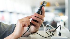 Female,Hands,Holding,And,Using,Smartphone,While,Charging,It,In